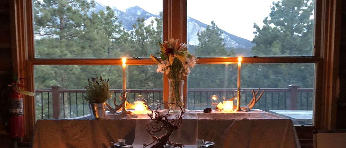 candles, flowers, antlers on a table with a mountain backdrop through the window